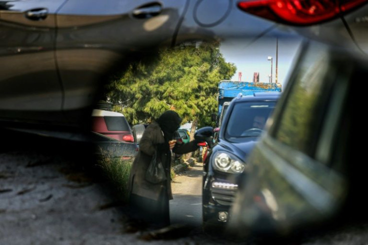 A woman begs drivers for money in Lebanon's capital Beirut, where people are struggling amid a dire economic crisis