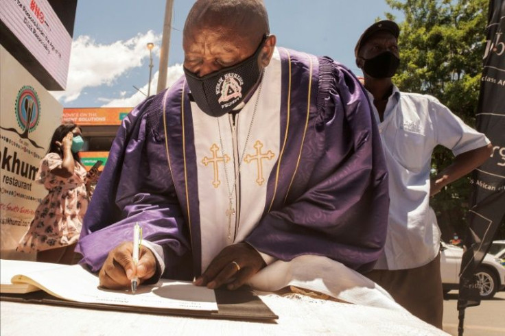 An Anglican priest signs a book of rememberance during a memorial service in Desmond Tutu's honour in front of his house in Soweto