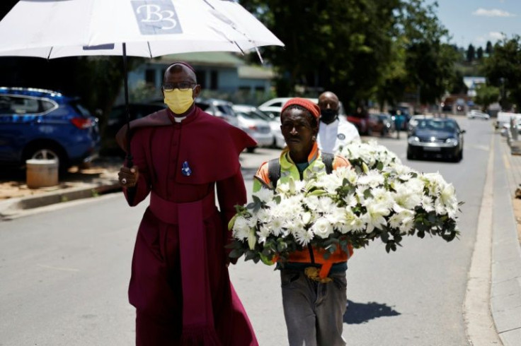 Johannesburg Bishop Stephen Moreo walks alongside a man bearing a wreath of flowers to Tutu's family home as those who knew him paid tribute to a man who was "the voice of the voiceless"