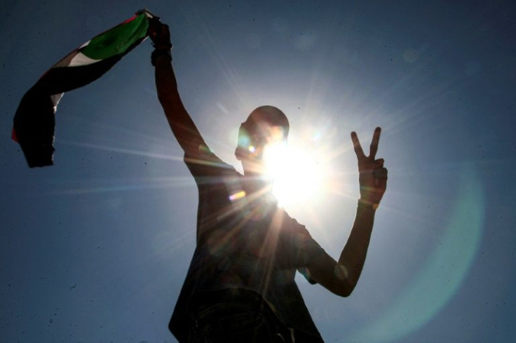 A Sudanese protester flashes a victory sign and waves a flag during a demonstrations demanding civilian rule in Khartoum on December 25; more protests are planned for Thursday