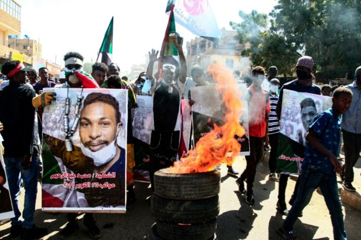 Sudanese demonstrators carry posters of protesters killed during earlier rallies, as they march in Khartoum against the army on December 30