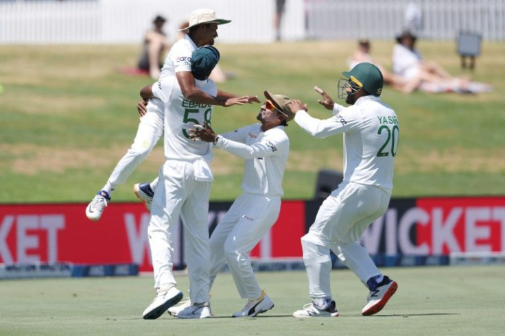 Taijul Islam (L) is lifted by Ebadot Hossain as Bangladesh celebrate the final wicket of New Zealand's Trent Boult during the fifth day of the first cricket Test match between New Zealand and Bangladesh at the Bay Oval in Mount Maunganui on January 5, 202