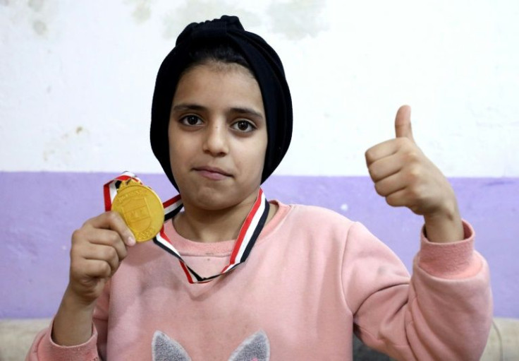 Young boxer Hajer Ghazi poses with a medal; she is part of a movement of women and girls taking up a range of sports, also including kickboxing