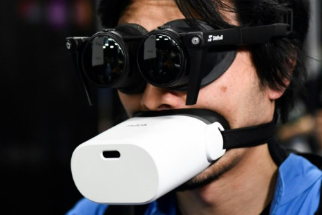 An attendee tries out the Shiftall Megane X virtual reality headphones and microphone for metaverse experiences during the Consumer Electronics Show (CES) in Las Vegas, Nevada
