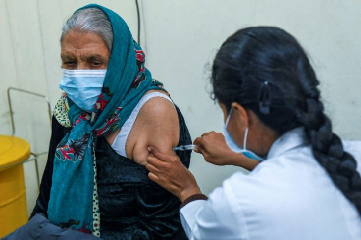 A health worker in India inoculates a woman with a third 'booster' dose of the Covid-19 vaccine as the country sees an Omicron-driven surge in cases