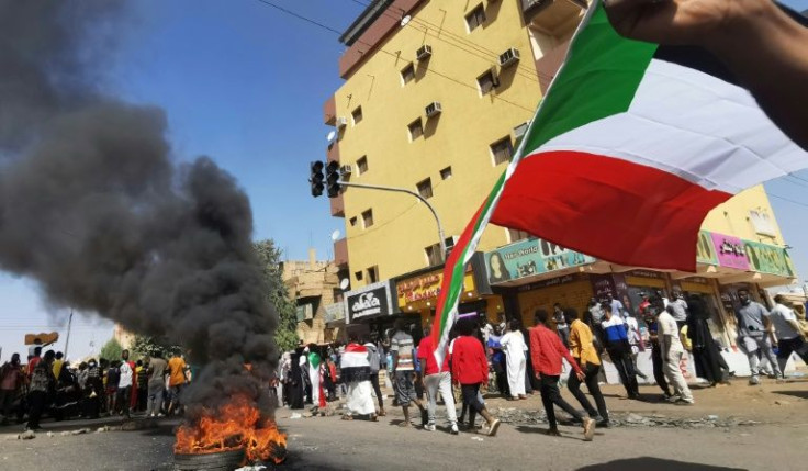 Sudanese protesters walk past burning tyres as they rally against the October 2021 military coup, in the capital Khartoum, on January 9, 2022