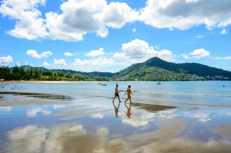 Tourists walk on a beach on the Thai island of Phuket