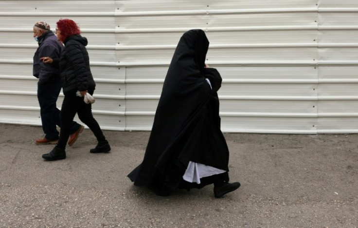 An ultra-Orthodox Jewish woman walks in the east Jerusalem neighborhood of Sheikh Jarrah. Haredim are not a homogeneous group, but each professes to live in strict accordance with Jewish law