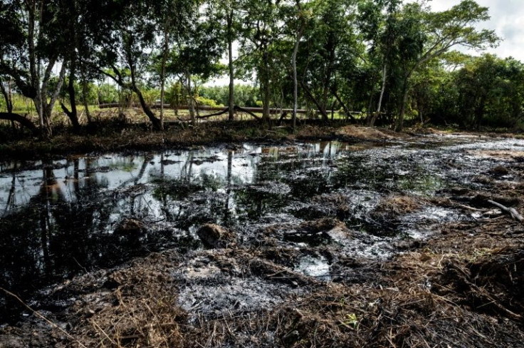 A man carries buckets while working to clean up an oil spill near a PDVSA pipeline in Voladero, Monagas state