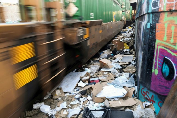 A train carrying shipping containers passes through a section of Union Pacific train tracks littered with thousands of opened boxes and packages stolen from cargo shipping containers on January 14, 2022