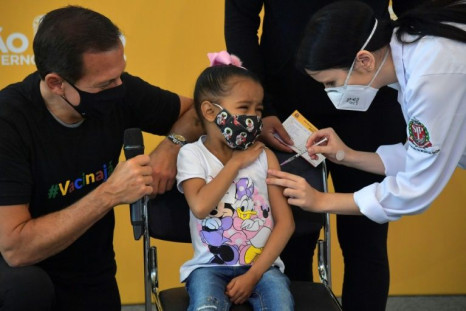 A child receives a Covid-19 vaccine in Brazil's Sao Paulo with local governor Joao Doria (L) looking on