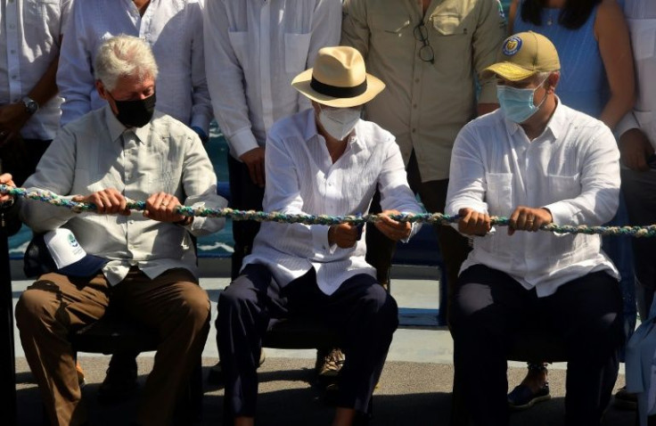 Ecuador's President Guillermo Lasso (C) cuts a rope made of materials collected from coastal cleanups to symbolically inaugurate the expanded Galapagos marine reserve, with former US president Bill Clinton (L) and Colombia's President Ivan Duque