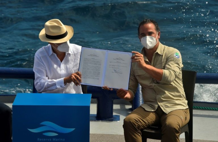 Ecuador's President Guillermo Lasso (L) and Environment Minister Gustavo Manrique show the decree for the expansion of the Galapagos marine reserve