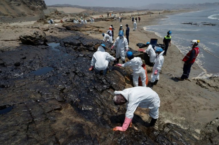 Workers on a Peruvian beach clean up an oil spill caused by abnormal waves triggered by a massive underwater volcanic eruption half a world away in Tonga