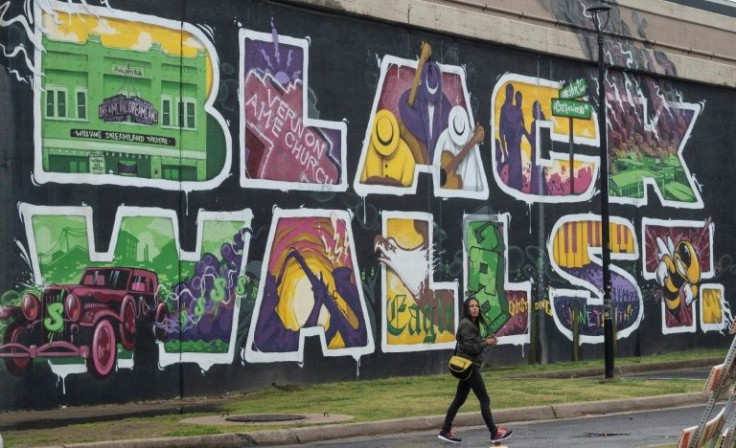 A pedestrian passes in front of a mural commemorating the 1921 Tulsa race massacre in June 2021