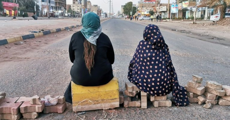 Sudanese women sit atop a brick barricade at 60th Street on January 18, 2022 in the capital Khartoum as part of a civil disobedience campaign following the killing of seven anti-coup demonstrators