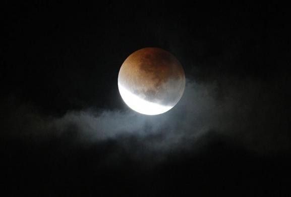 A lunar eclipse is visible through a gap in storm clouds over Sydney in the early hours of June 16, 2011.