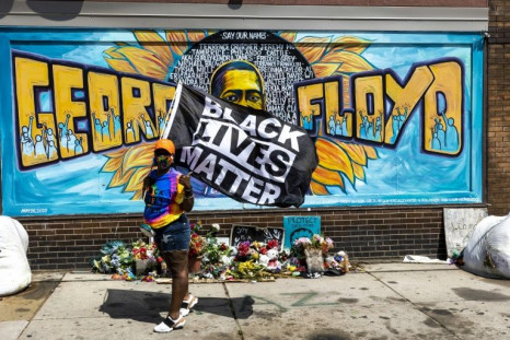 A woman holds a Black Lives Matter flag front of a mural of George Floyd in Minneapolis, Minnesota