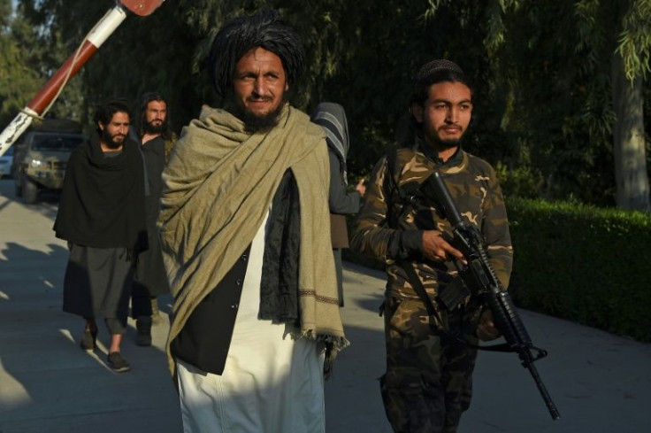 A member of the Taliban's department of the Promotion of Virtue and the Prevention of Vice walks the streets of Jalalabad with an armed escort