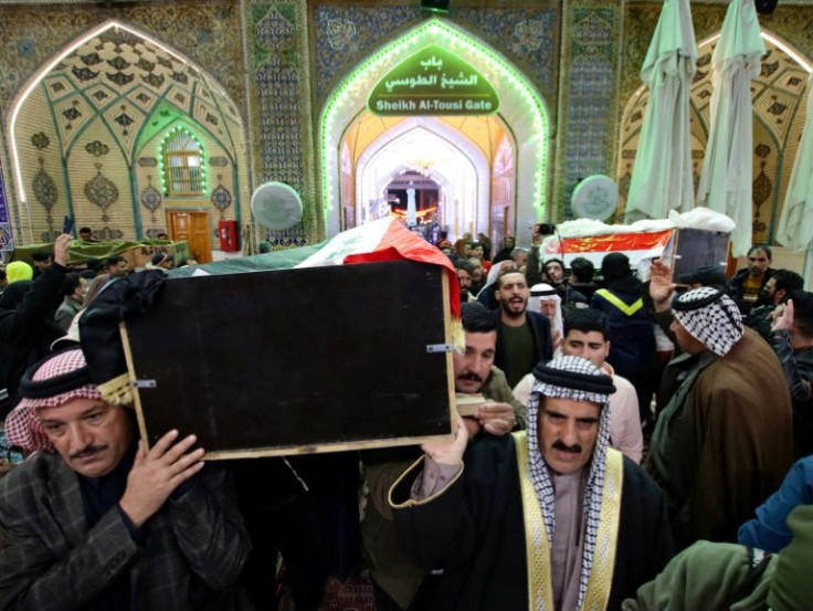 Mourners carry the caskets of two of the 11 Iraqi soldiers, killed in an attack by the Islamic State group on a base in eastern Iraq