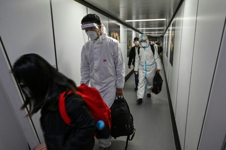 Passengers, some wearing full personal protective equipment, disembarking from their plane at Pudong International Airport in Shanghai on January 18, 2022