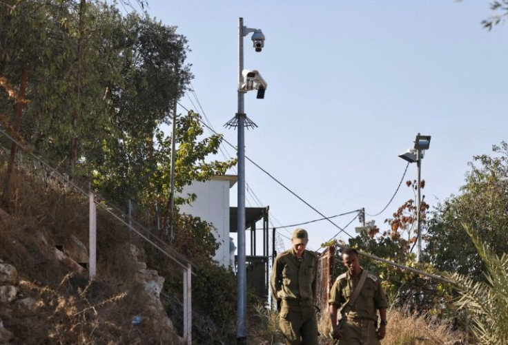 In this file photo taken on November 9, 2021, Israeli soldiers walk past surveillance cameras in the flashpoint Palestinian city of Hebron