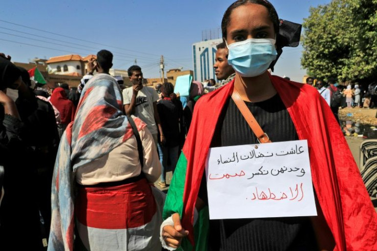 A female Sudanese protester wears a handwritten placard which reads in Arabic: "Long live the struggle of women, they alone can break the silence of oppression"
