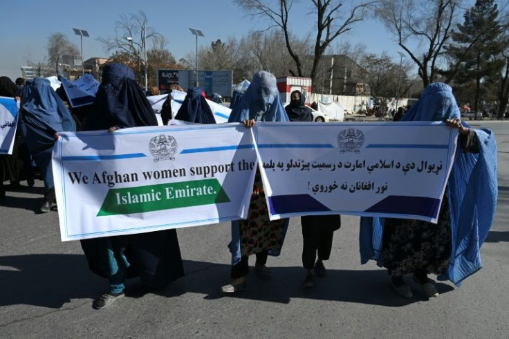 Burqa-clad women hold a banner during a protest in support of the Taliban regime