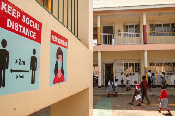 Pupils walk past wall posters calling for Covid-safety measures at Nalya Primary school in Kampala