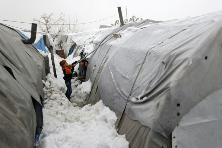 A Syrian boy clears snow from a tent in a displaced persons' camp outside the rebel-held city of Jisr al-Shughur