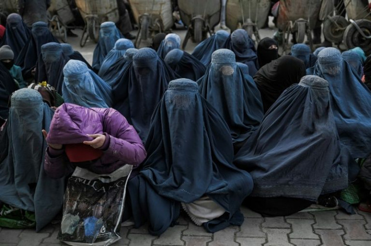 Women wearing burqas wait for free bread in front of a bakery in Kabul on January 24, 2022