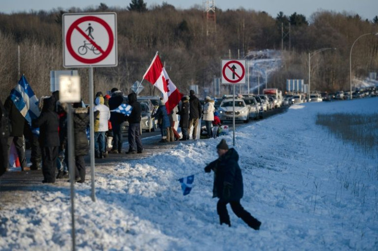 People gather along the trans-Canadian highway in Quebec province on January 28, 2022 in support of a convoy of truckers protesting vaccine mandates
