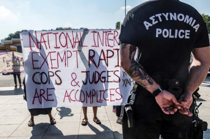 A Cyprus police officer stands guard as women demonstrate on September 16, 2021 in front of Nicosia's supreme court, in support of the young British woman