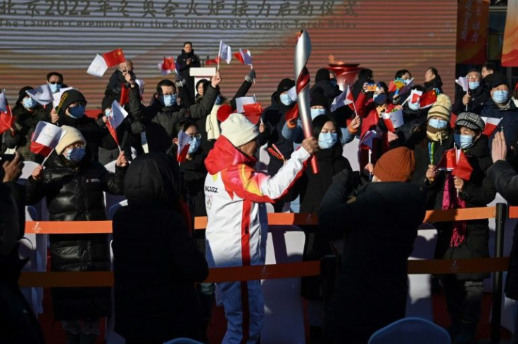 Audiences cheer as Luo Zhihuan, China's first world speed skating champion, holds the Olympic torch during the relay