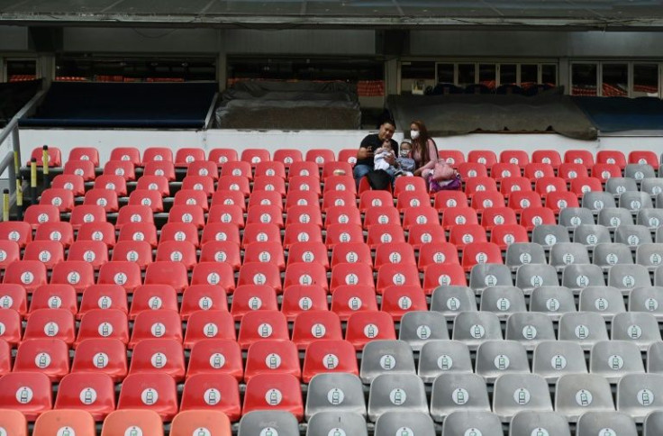 A couple waits for the start of the World Cup qualifier between Mexico and Costa Rica, played in a near-empty stadium