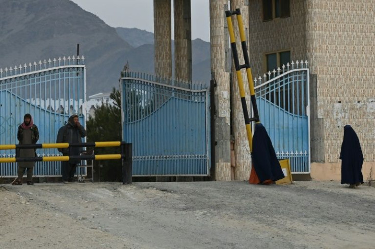 Two women in burqas enter Laghman University, watched by a pair of Taliban fighters