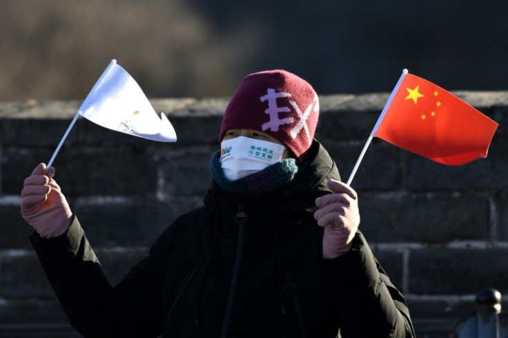A woman holds a Chinese flag and a Beijing 2022 flag on the Great Wall