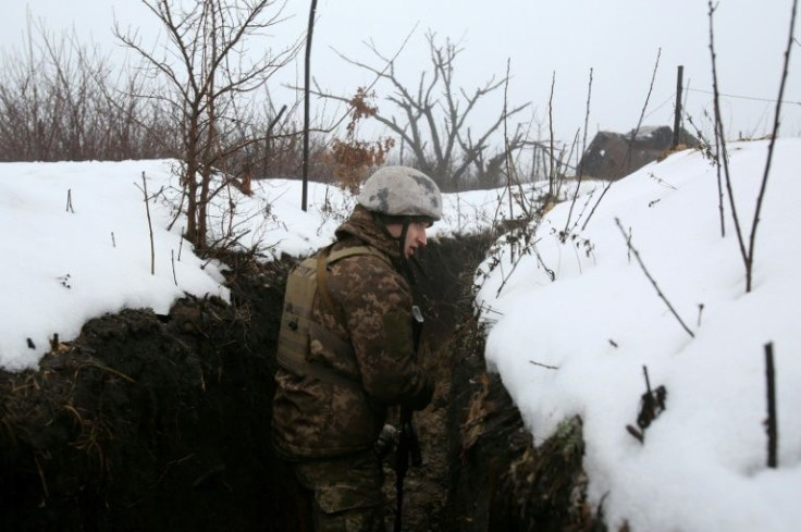 A Ukrainian serviceman walks along a snow covered trench