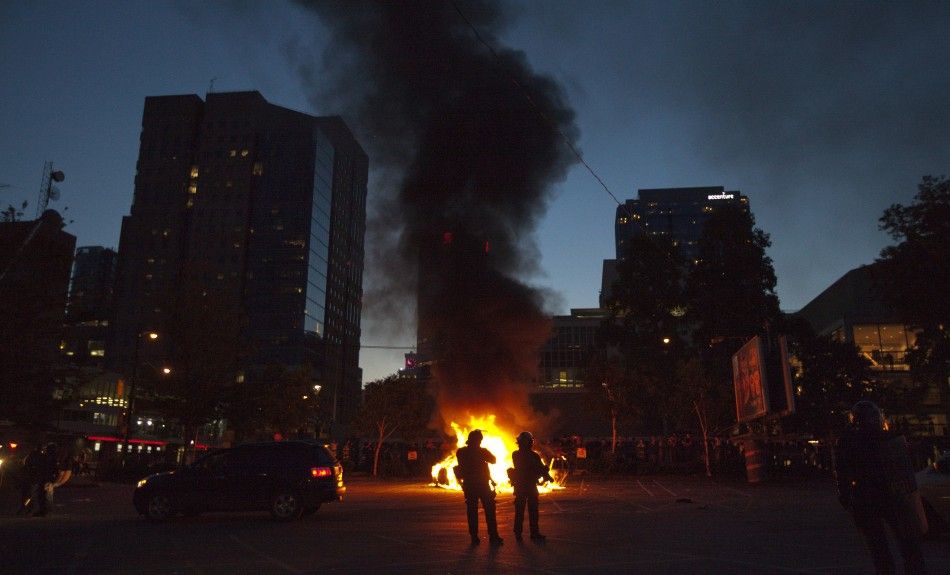 Police stand guard as police cars burn in the background after Game 7 of the NHL Stanley Cup hockey playoff between the Canucks and the Bruins in Vancouver