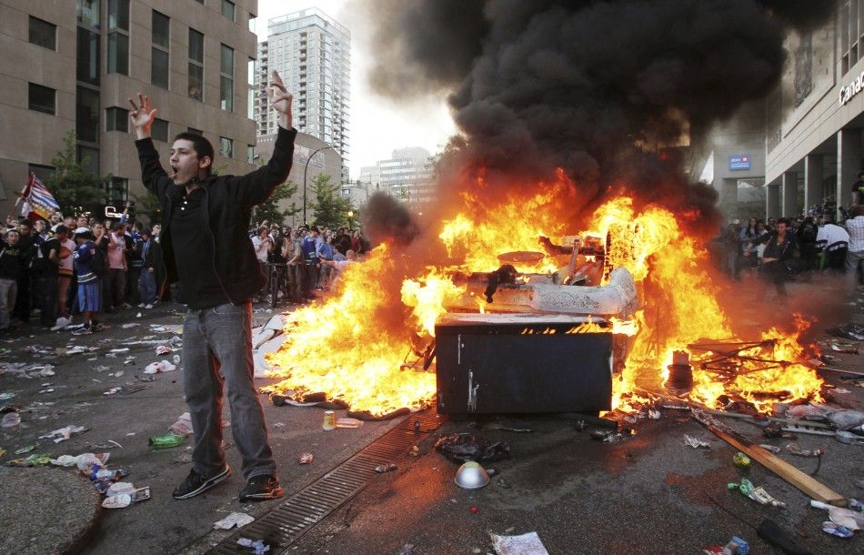 A Canucks fan screams in front of an overturned burning pickup truck in downtown Vancouver, British Columbia during riots after the Canucks lost the NHL Stanley Cup playoffs to the Bruins