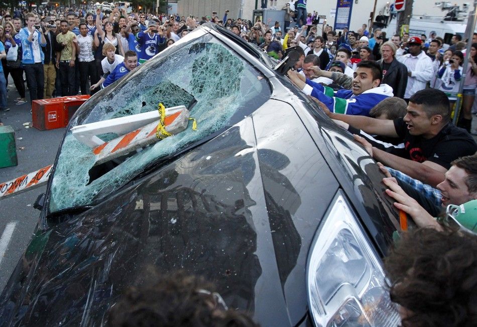 Canucks fans push over a vehicle as they react to their team039s loss to the Bruins in the NHL Stanley Cup final hockey game in Vancouver