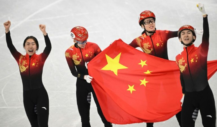 China's quartet celebrate victory in the mixed team relay short track speed skating event, the host nation's first gold of the Games