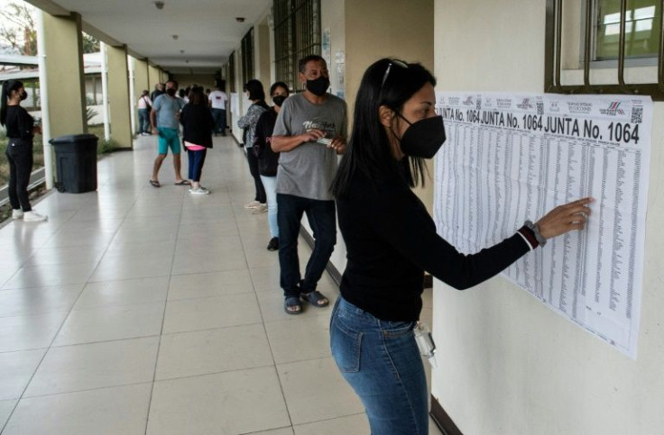 A woman in San Jose, Costa Rica looks at a chart to find the polling station where she needs to vote during her country's presidential elections, a wide open race featuring more than two dozen candidates