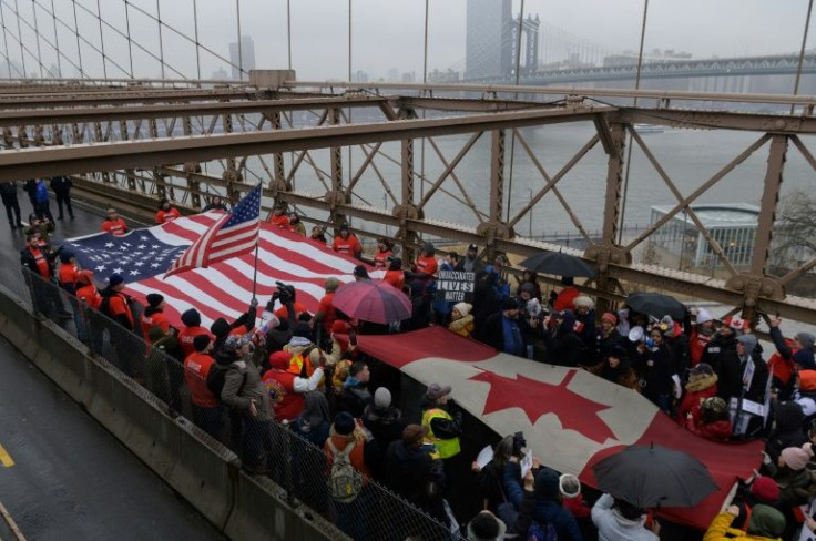 New York City workers opposed to Covid vaccine mandates march across the Brooklyn Bridge carrying giant US and Canadian flags
