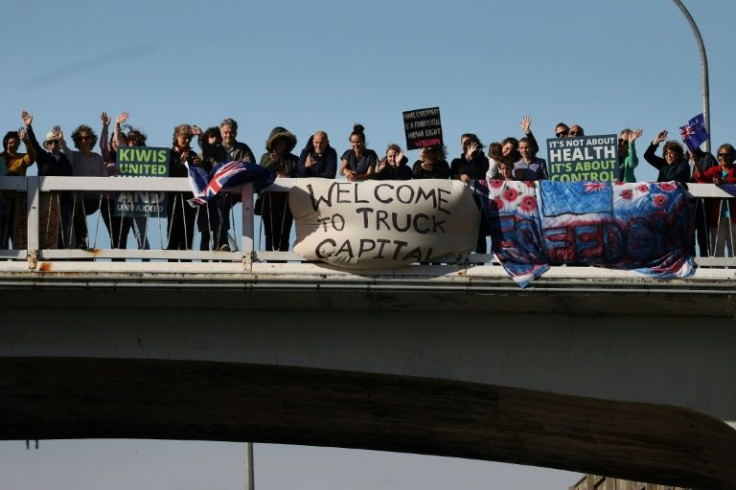 Protesters stand on an overpass to welcome a protest convoy of trucks and other vehicles in Wellington, New Zealand