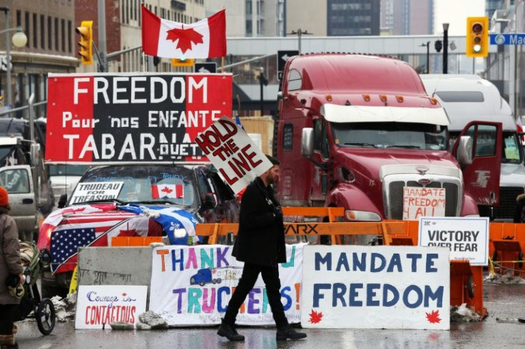 A protester walks in front of parked trucks as demonstrators continue to protest vaccine mandates on February 8, 2022 in Ottawa, Canada