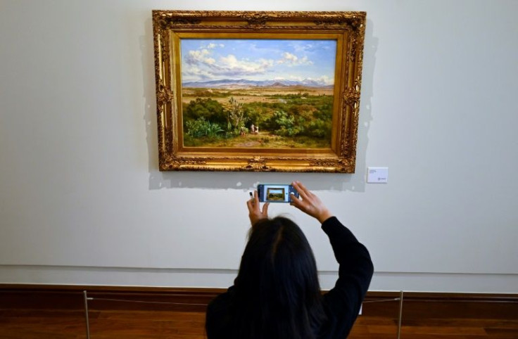 A woman takes a picture of Mexican artist Jose Maria Velasco's 1888 painting "Valle de Mexico" (Mexico Valley) at the Banamex Cultural Foundation in Mexico City