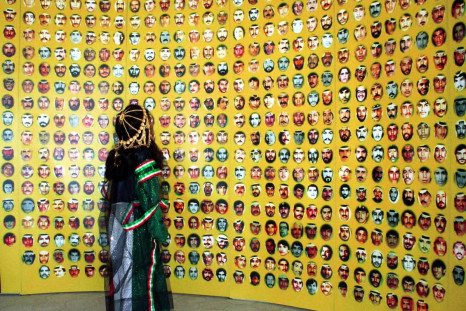 A young girl in Kuwaiti national dress looks up at pictures of hundreds of people missing since the 1990-1991 Gulf Crisis, on display at a major celebration marking the end of Iraq's occupation of Kuwait 10 years ago, in Kuwait City, February 25, 2001. 