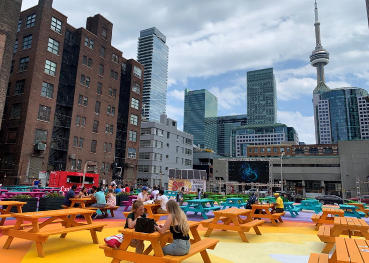 People sit at picnic tables in the RendezViews outdoor patio project in Toronto, Canada, June 20, 2021.