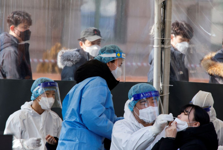 A healthcare worker collects a swab sample from a woman to test for the coronavirus disease (COVID-19), at a temporary testing site set up at a railway station, in Seoul, South Korea, February 10, 2022.  